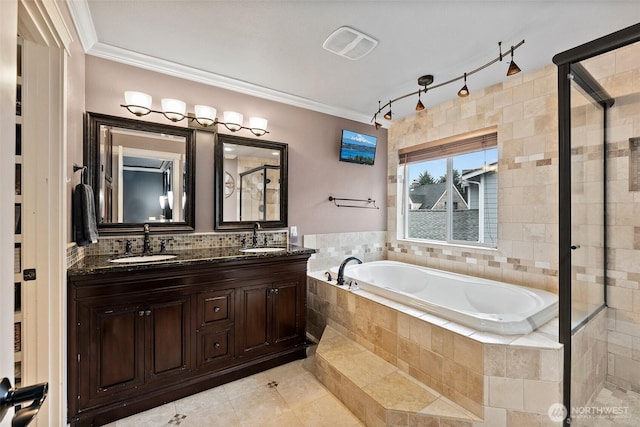 bathroom with crown molding, a garden tub, and a sink