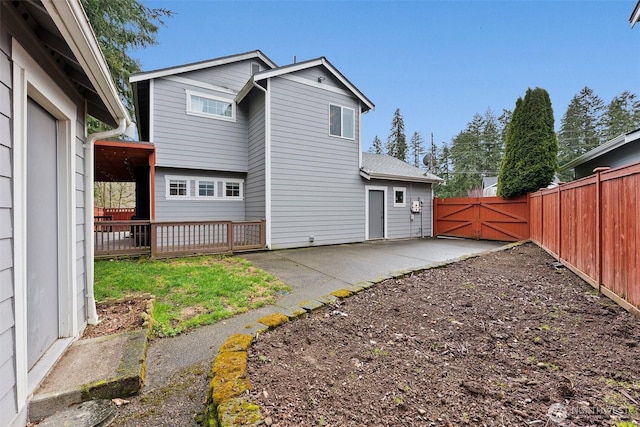 rear view of property with a patio area, fence, and a gate