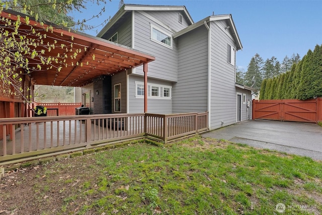 back of house featuring a lawn, fence, a deck, and a gate