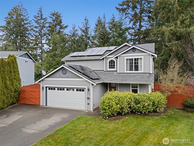 traditional-style home featuring a front lawn, fence, roof mounted solar panels, an attached garage, and a gate