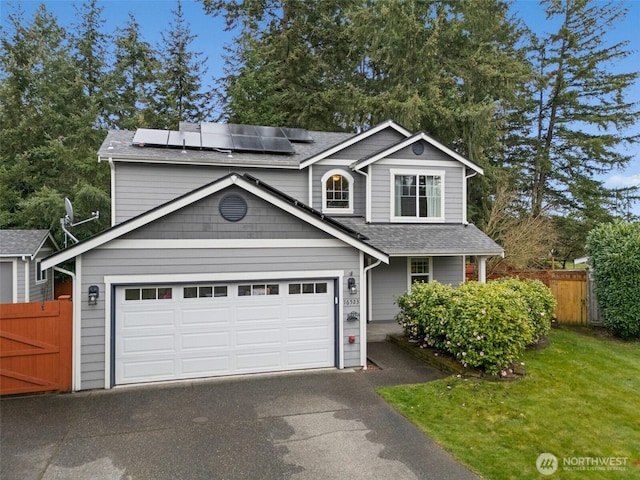 traditional-style home with solar panels, aphalt driveway, fence, and roof with shingles