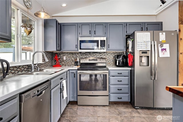 kitchen featuring lofted ceiling, a sink, decorative backsplash, light countertops, and stainless steel appliances