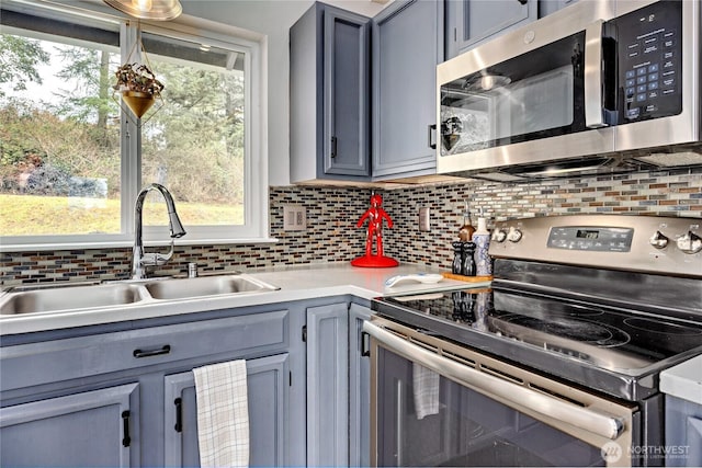 kitchen with decorative backsplash, appliances with stainless steel finishes, gray cabinetry, and a sink