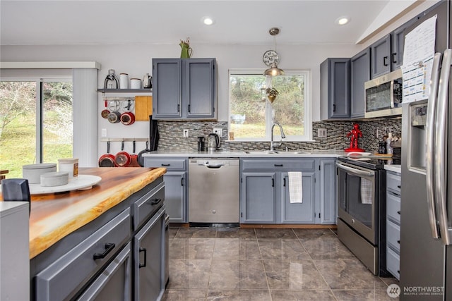 kitchen featuring backsplash, butcher block countertops, recessed lighting, appliances with stainless steel finishes, and a sink