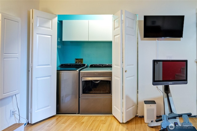 laundry area featuring cabinet space, washing machine and dryer, and light wood-style floors