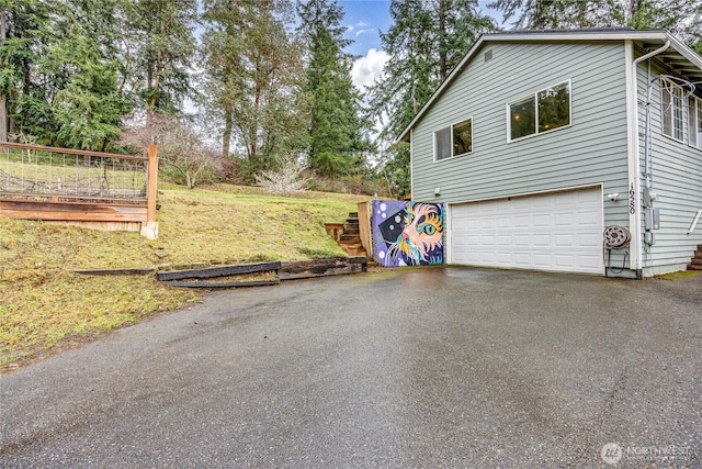 view of side of property with aphalt driveway and a garage