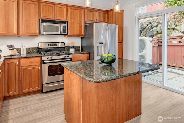 kitchen with light wood-style flooring, a center island, brown cabinetry, and stainless steel appliances