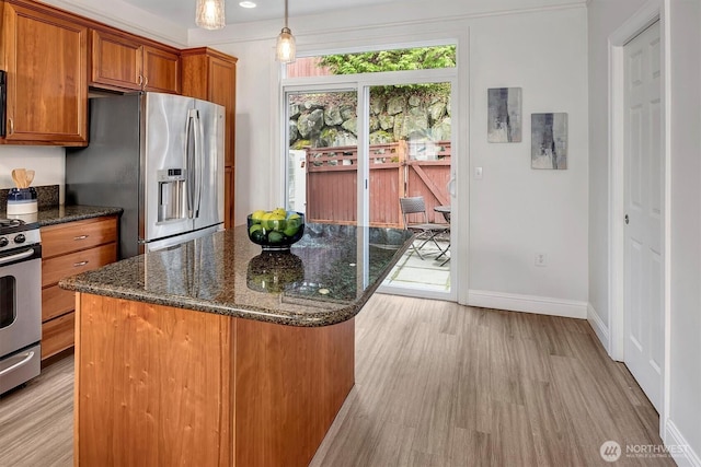 kitchen featuring brown cabinets, a kitchen island, light wood-style floors, appliances with stainless steel finishes, and baseboards