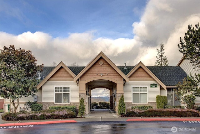 craftsman inspired home featuring stone siding and a shingled roof