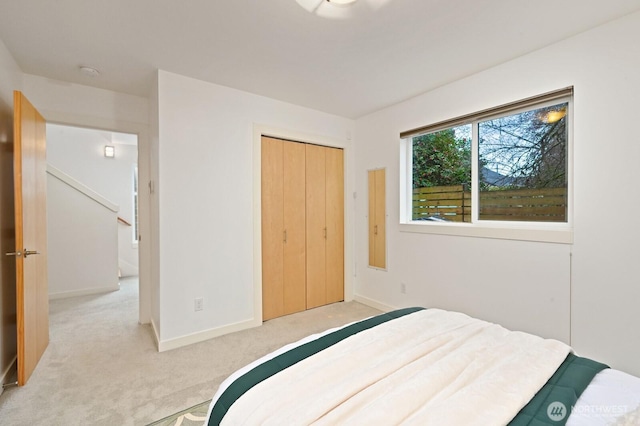 bedroom featuring a closet, light carpet, and baseboards