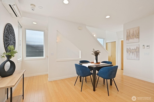 dining room featuring recessed lighting, light wood-style flooring, baseboards, and a wall unit AC