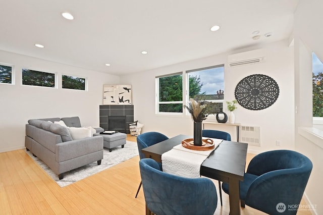 dining space with visible vents, wood finished floors, a wall unit AC, recessed lighting, and a fireplace