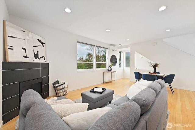 living area featuring light wood-style flooring, recessed lighting, baseboards, and a wall mounted AC