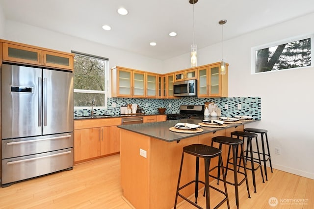 kitchen featuring dark countertops, decorative backsplash, a peninsula, stainless steel appliances, and a sink