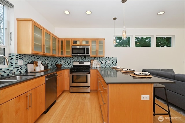 kitchen with a sink, stainless steel appliances, dark countertops, and a peninsula