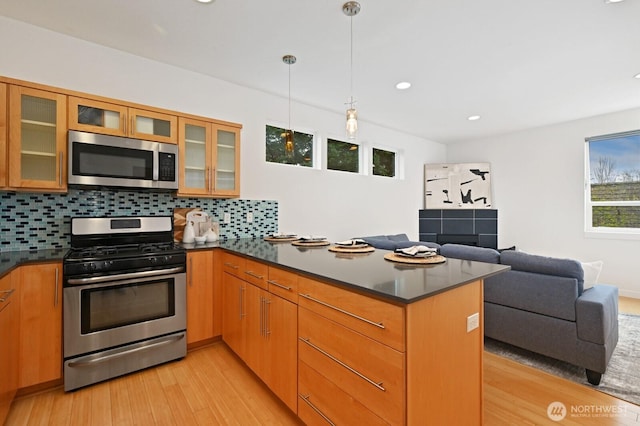 kitchen featuring a peninsula, dark countertops, open floor plan, and appliances with stainless steel finishes