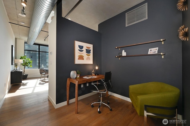 office area with wood finished floors, visible vents, and baseboards