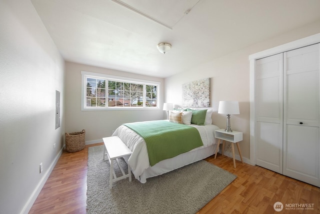 bedroom with wood finished floors, baseboards, and a closet