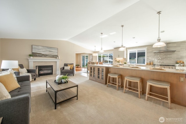 living room featuring a glass covered fireplace, lofted ceiling, and light carpet