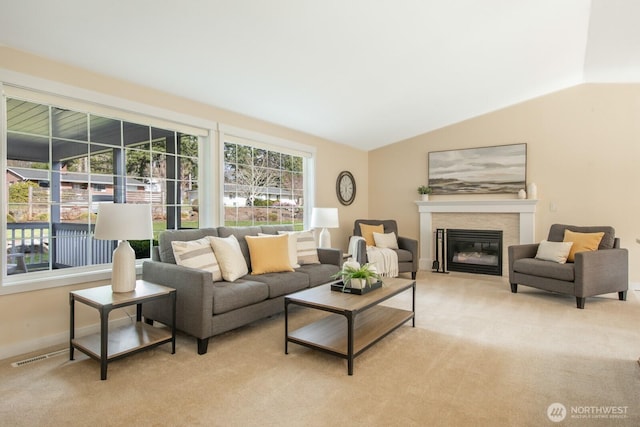 living area featuring light carpet, a glass covered fireplace, baseboards, and lofted ceiling