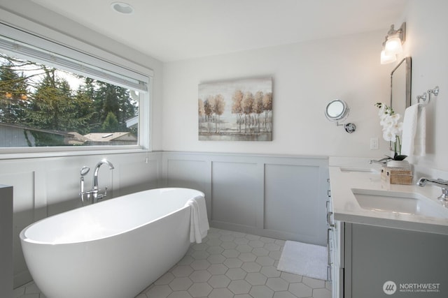 bathroom featuring a sink, a wainscoted wall, a soaking tub, and a decorative wall