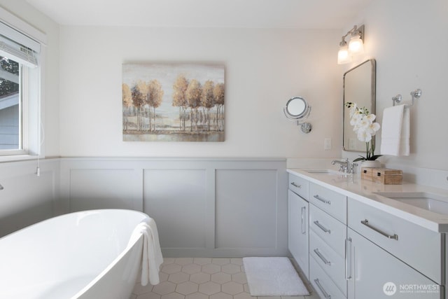 full bathroom with wainscoting, a freestanding bath, and a sink