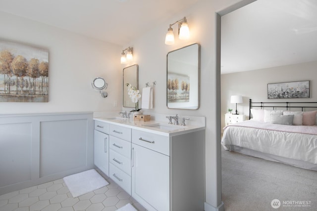 ensuite bathroom with double vanity, a wainscoted wall, a decorative wall, and a sink