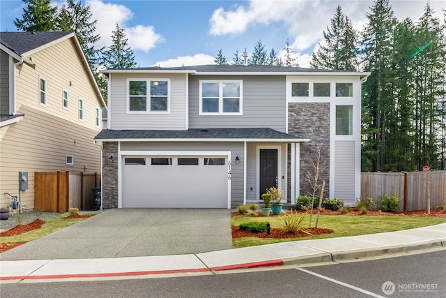 view of front of house with stone siding, an attached garage, driveway, and fence