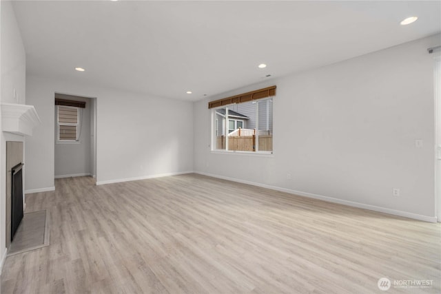 unfurnished living room featuring light wood-style flooring, recessed lighting, a fireplace, and baseboards