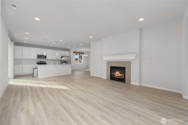 unfurnished living room featuring visible vents, baseboards, a fireplace, recessed lighting, and light wood-style floors