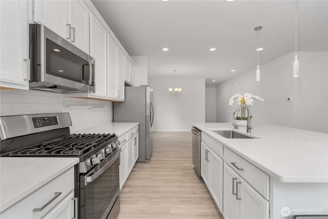 kitchen featuring white cabinets, appliances with stainless steel finishes, light countertops, and a sink