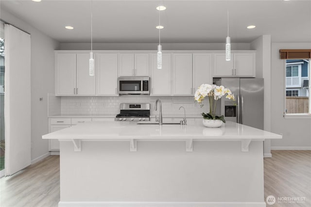 kitchen with a sink, stainless steel appliances, tasteful backsplash, and a breakfast bar