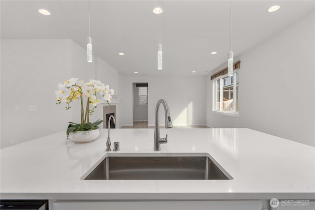 kitchen featuring recessed lighting, pendant lighting, light countertops, and a sink