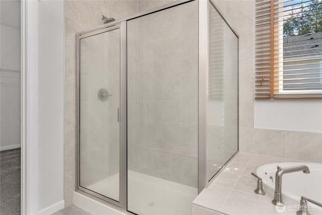 bathroom with baseboards, plenty of natural light, a garden tub, and a shower stall