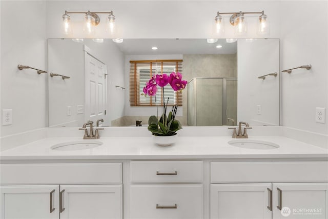 bathroom with double vanity, a shower stall, and a sink