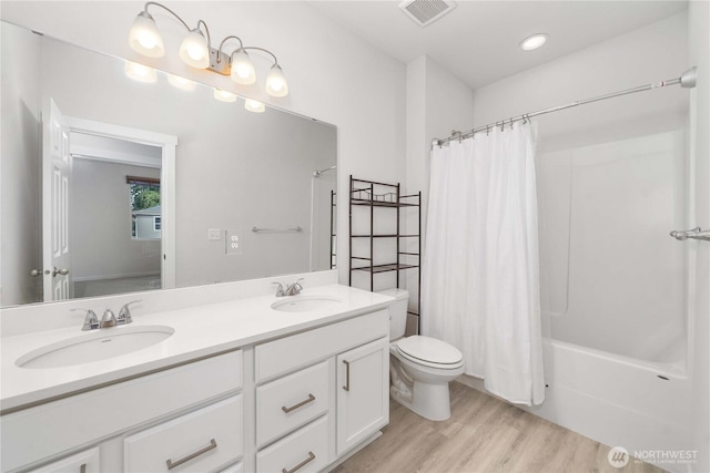 bathroom with visible vents, toilet, wood finished floors, and a sink