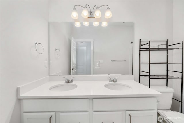 bathroom with double vanity, toilet, and a sink