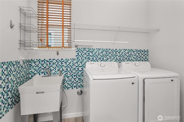 washroom with washer and clothes dryer, laundry area, tile walls, and a sink