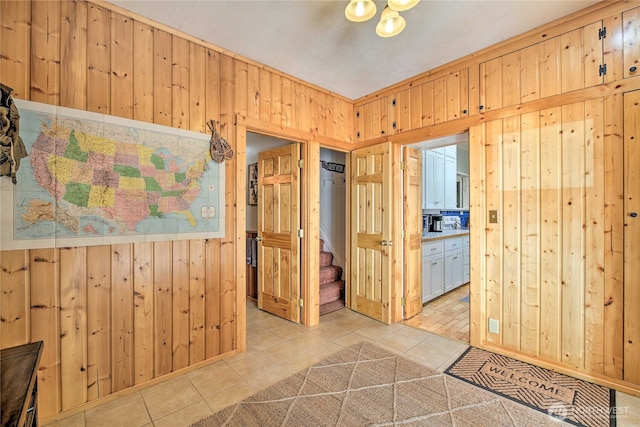 interior space featuring stairs, wooden walls, and light tile patterned floors