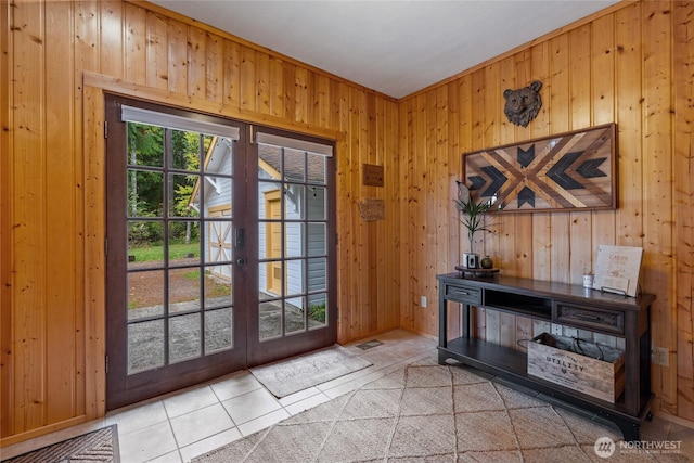 doorway with light tile patterned floors, wooden walls, french doors, and baseboards