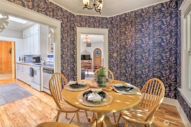 dining space with light wood-type flooring, visible vents, a notable chandelier, ornamental molding, and wallpapered walls