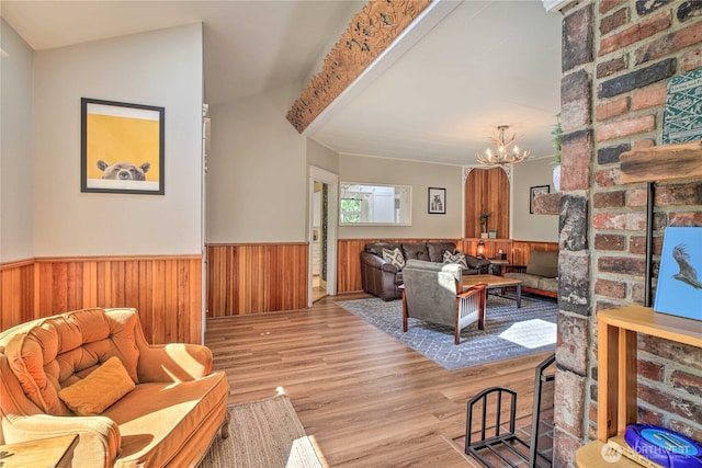 living area with a wainscoted wall, wooden walls, wood finished floors, and a chandelier