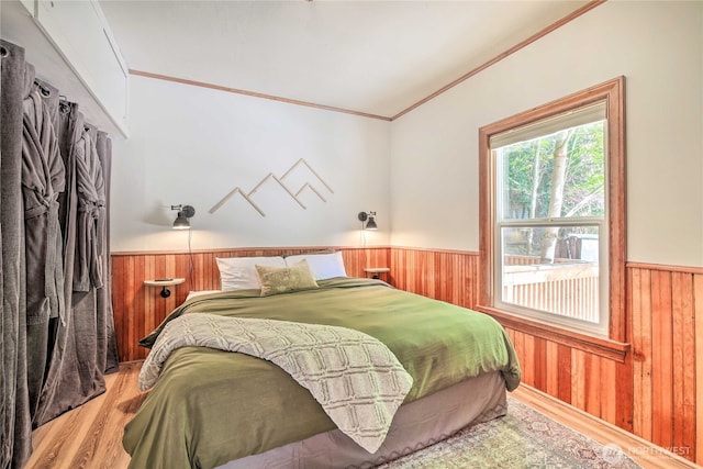 bedroom featuring wooden walls, light wood-style floors, and wainscoting