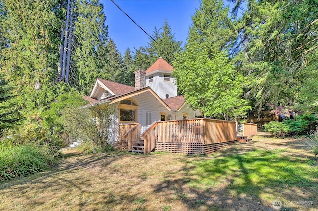 back of house featuring a wooden deck, a lawn, and a chimney