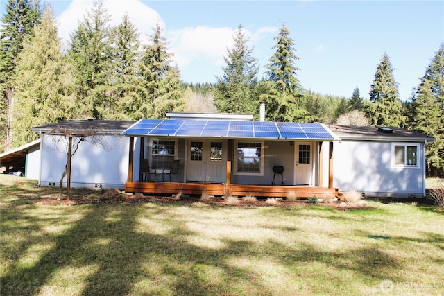 rear view of house with crawl space, roof mounted solar panels, a yard, and a porch