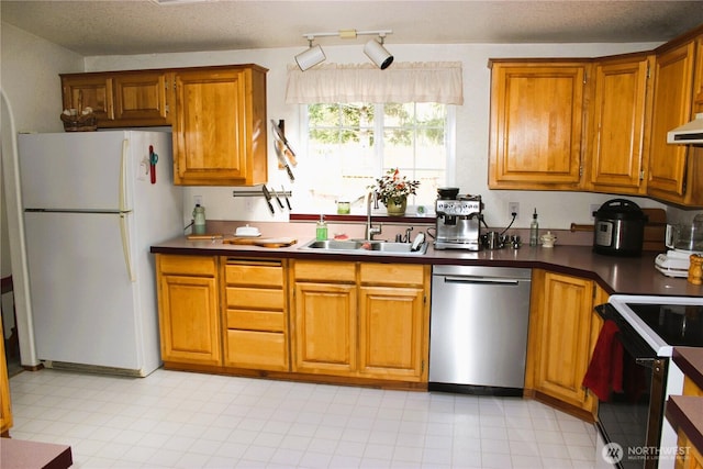 kitchen featuring brown cabinets, a sink, stainless steel dishwasher, black range with electric cooktop, and freestanding refrigerator