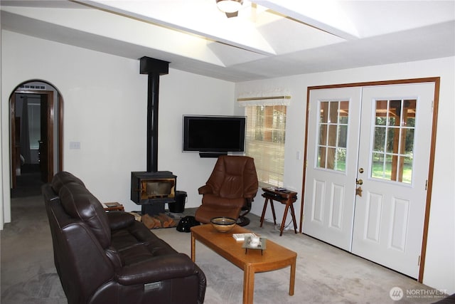 living room with light carpet, french doors, a wood stove, and lofted ceiling