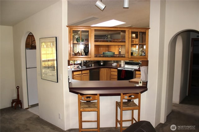 kitchen with range with electric cooktop, black dishwasher, freestanding refrigerator, arched walkways, and glass insert cabinets