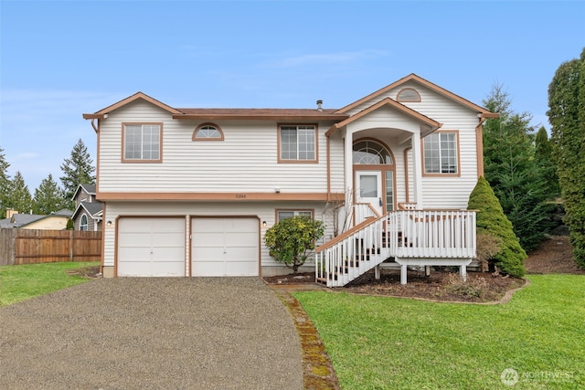 raised ranch featuring a front lawn, an attached garage, fence, and driveway