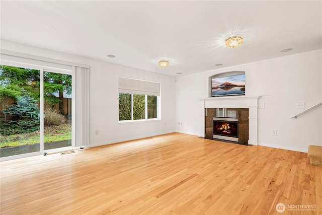 unfurnished living room with wood finished floors, baseboards, and a premium fireplace